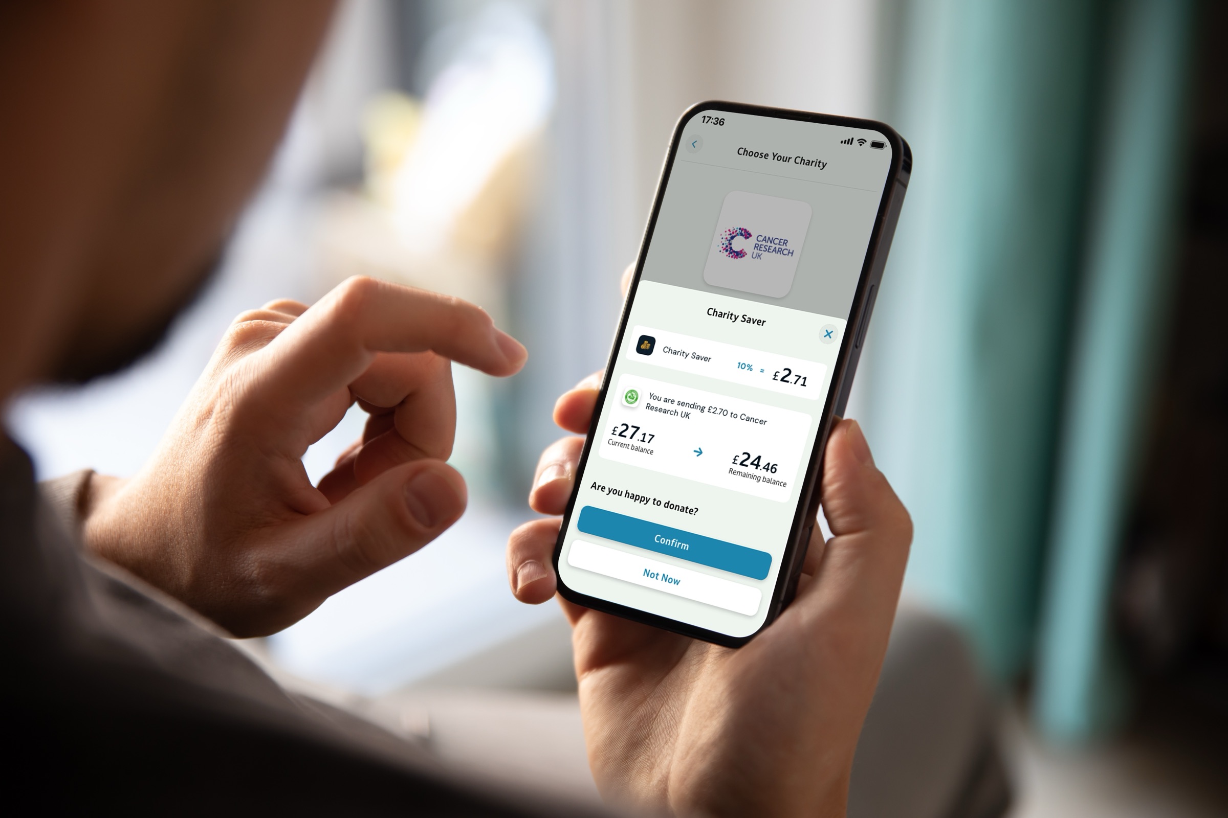 A Monzo charity pot confirmation screen on a phone, held in both hands